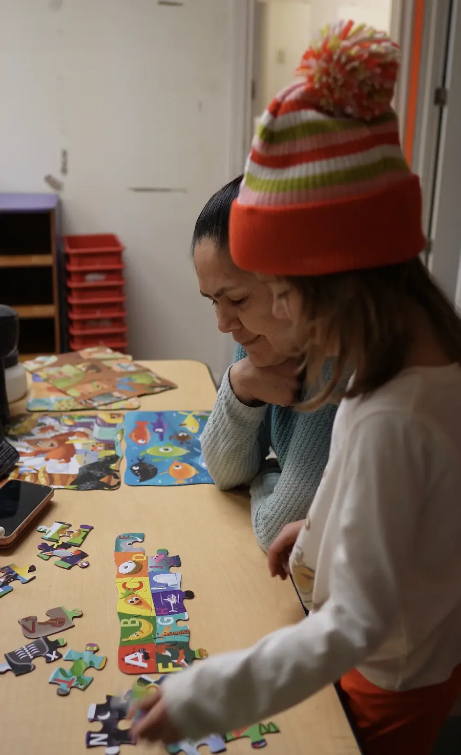 Owner Nydia Keasey doing a puzzle with a child at Happy Carousel Daycare