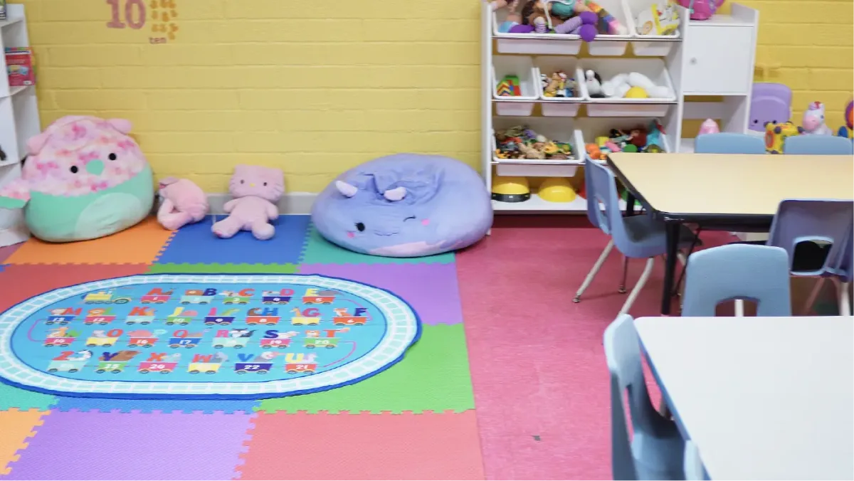 The preschool room at Happy Carousel Daycare — number play rug, bean bags, and learning shelves
