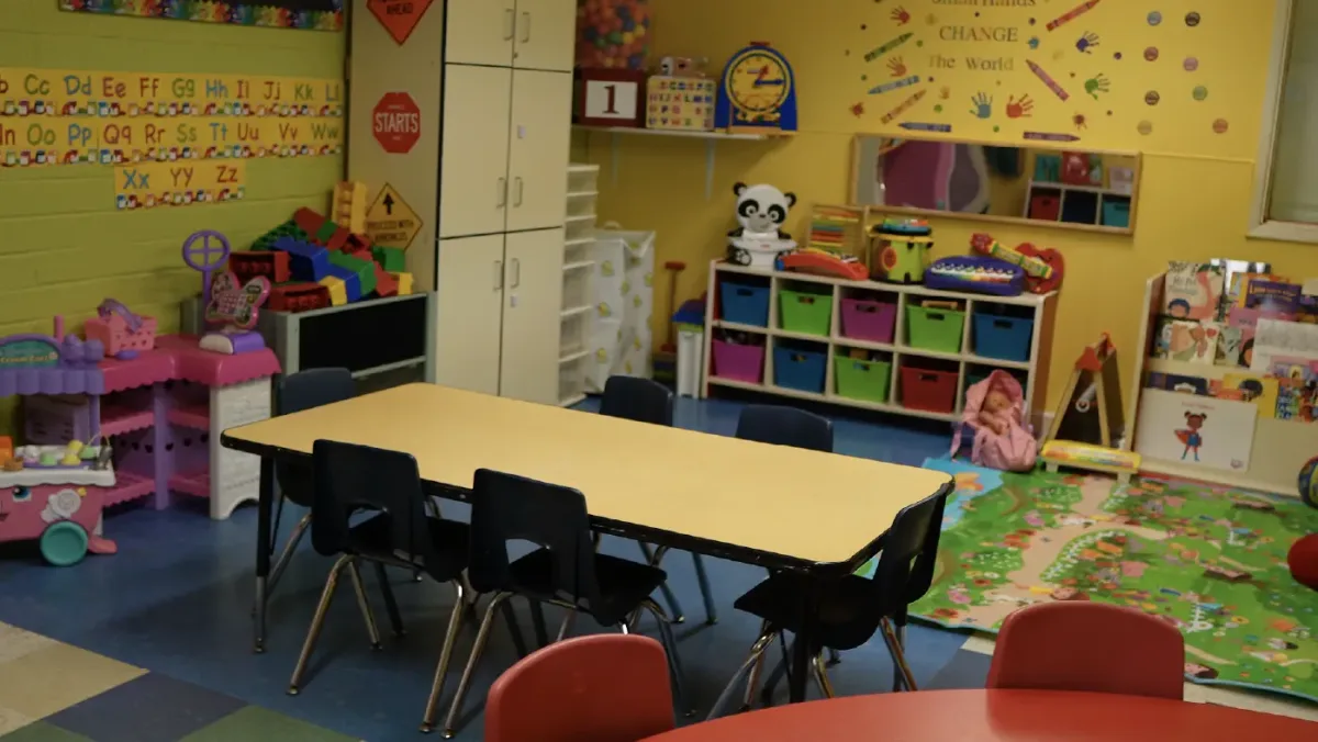 The toddler room with low tables, chairs, and toy shelves